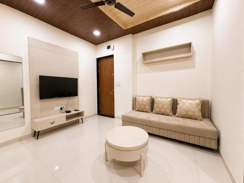 a living room with a couch and a flat screen tv at Hotel Aventus Suites Indore in Indore