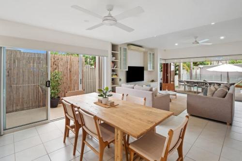 a dining room and living room with a wooden table and chairs at Pet Friendly Modern Oasis with Private Pool in Noosaville