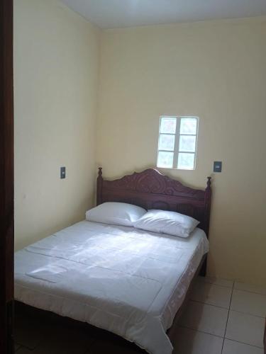 a bedroom with a bed with white sheets and two windows at Ap completo 01 quarto com ar condicionado, wi-fi in Viçosa