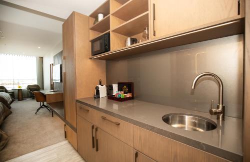 a kitchen with a sink and a living room at Distinction Invercargill Hotel in Invercargill