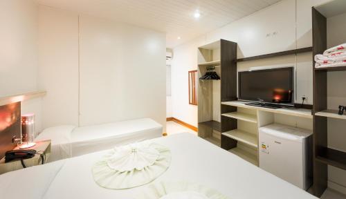 una camera da letto bianca con un letto e una TV di Hotel Brasil a Penha