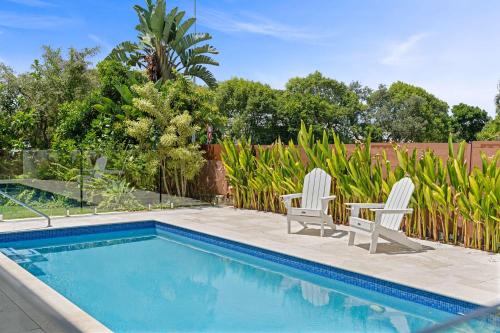a swimming pool with two white chairs next to a fence at Southwind in Sunrise in Sunrise Beach