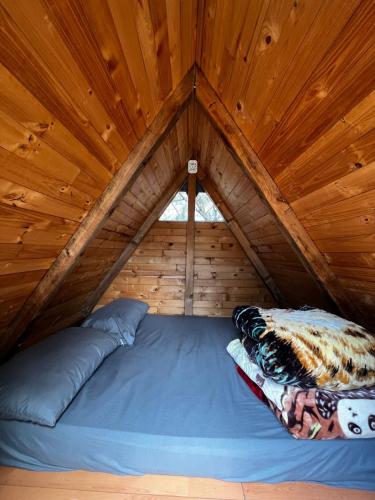a bed in a cabin with a wooden ceiling at Mini Cabaña Roca Glamping in Suesca