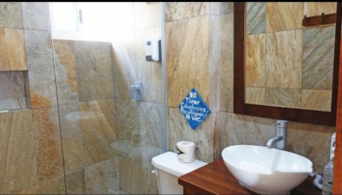 a bathroom with a sink and a toilet and a mirror at El Fuerte Beach Apartments in Mahahual