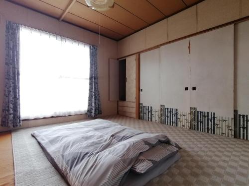 ein Schlafzimmer mit einem großen Bett und einem großen Fenster in der Unterkunft あらさんち in Asahikawa