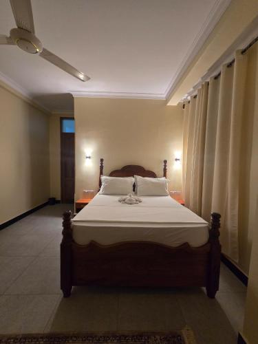 a bedroom with a large bed with white sheets at Al-mendhiry Apartment in Zanzibar City