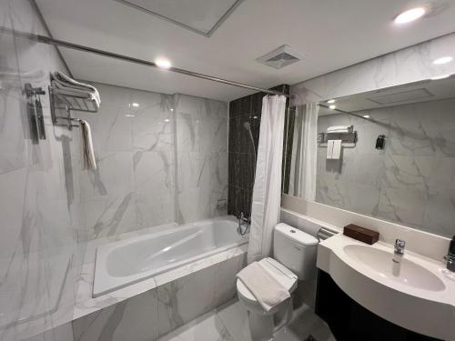 a bathroom with a tub and a toilet and a sink at Sahid Raya Hotel & Convention Yogyakarta in Yogyakarta