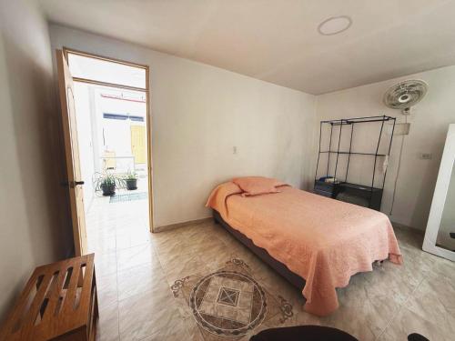 a bedroom with a bed with an orange blanket on it at Casa Aire y Luz in Pereira