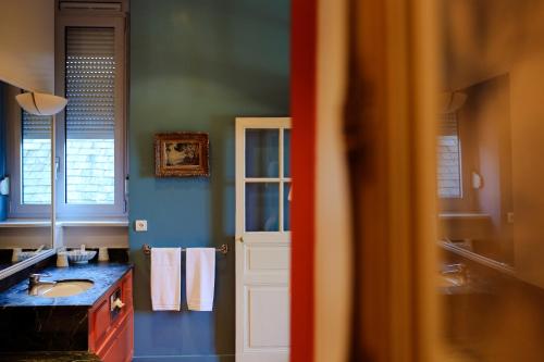 a blue bathroom with a sink and a mirror at La Chapelle Saint Martin in Nieul
