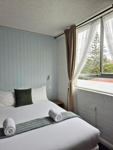 a bedroom with a bed and a large window at Little Coogee Hotel in Sydney