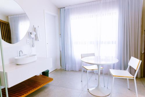 a bathroom with a sink and a table and chairs at Liiv Hub - Natal PontaNegra in Natal