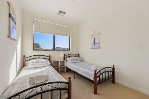 two beds in a room with a window at 41 Blanche Pde, Hindmarsh Island in Hindmarsh Island