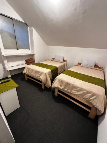 two beds in a small room with a window at Eco Bunnu Inn Santa Ana in Cusco