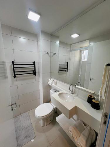 a bathroom with a toilet and a sink and a mirror at Apartamento com academia - Toledo in Toledo