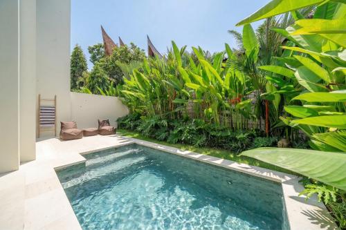 a swimming pool in a backyard with plants at Lily Villas - Rice Field Views Escape with Private Pool in Canggu