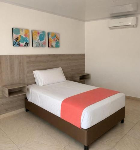 a bed in a bedroom with three paintings on the wall at Hotel Asturias in Girardot