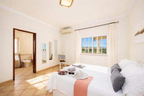 a white bedroom with a bed and a window at Villa Entrecolinas in São Bartolomeu de Messines