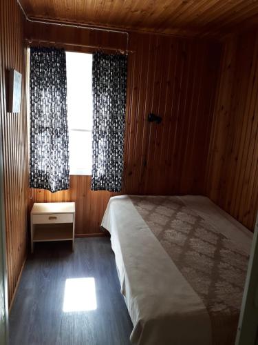 a bedroom with a large bed and a window at Pääsky Schwalbe-cabin by crater lake in Varpaisjärvi
