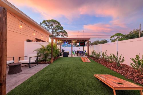 a backyard with a green yard with a wooden bench at 3BR - Beach & Trail - Bikes, Fire Pit, Mini-Golf in St. Petersburg
