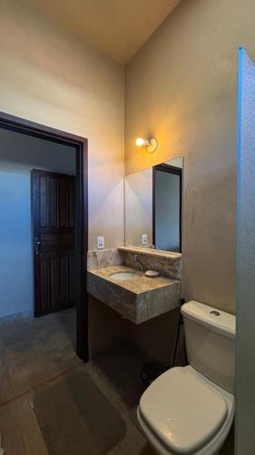 a bathroom with a toilet and a sink and a mirror at Alfa Beach in Cacha Pregos
