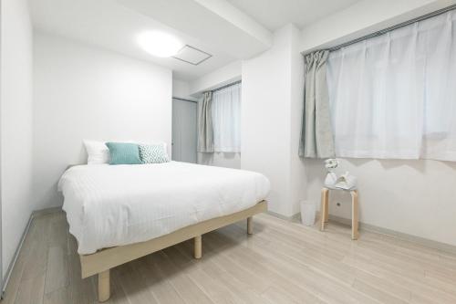 a white bedroom with a bed and a window at Sapporo Residence 14 in Sapporo