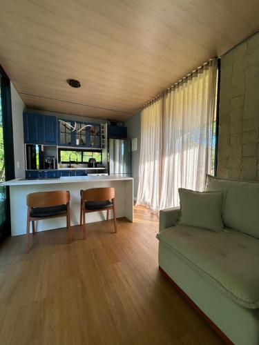 a living room with a couch and a kitchen at Chalé Moov in Guarapari