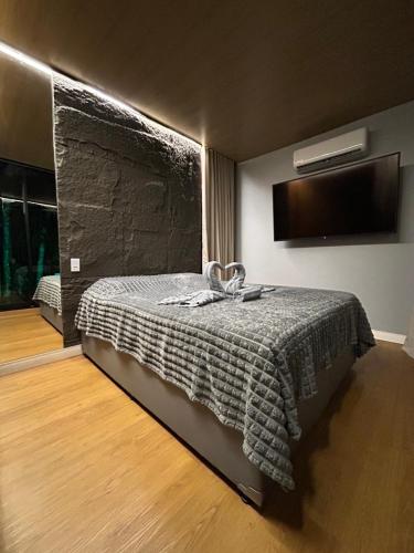a bedroom with a bed and a television on the wall at Chalé Moov in Guarapari