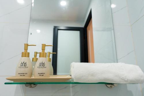 a bathroom with a mirror and a shelf with three soap bottles at Aura Retreat Boutique Hotel Hanoi in Hanoi