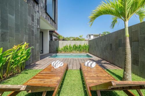 a backyard with a pool with a wooden bench and a palm tree at Grey Stones - Private Pool Villa with Rooftop in Ungasan