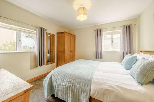 a bedroom with a white bed and two windows at 3 Bed in Poulton-le-fylde oc-41764 in Preesall