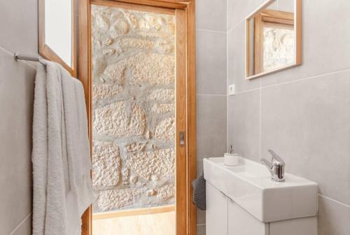 a bathroom with a sink and a stone wall at Goabio Apartment 3 Riverview in Porto