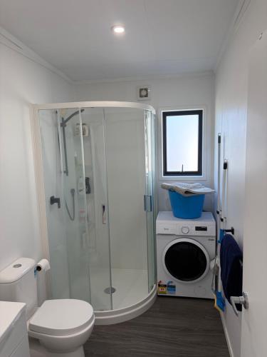 a bathroom with a shower and a washing machine at Whangamata Bach Life in Whangamata