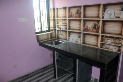 a kitchen with a sink and a shelf with dishes at Harsh Guest House in Cola