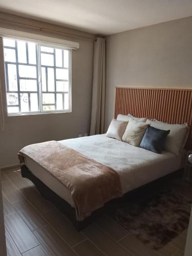 a bedroom with a large bed with a window at Depto Moderno Cerca de AIFA estacionamiento wifi in Santa Cruz Tecamac