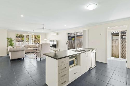 a kitchen with white cabinets and a living room at Comfortable 4BR Coomer Escape Close to Everything in Gold Coast