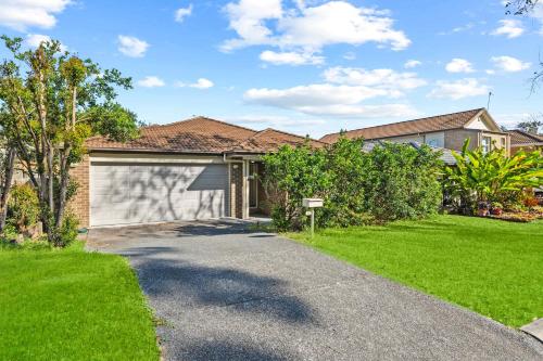 a house with a garage and a green yard at Comfortable 4BR Coomer Escape Close to Everything in Gold Coast