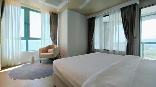 a bedroom with a bed and a chair and windows at La,mer Butik Hotel in Kota Kinabalu