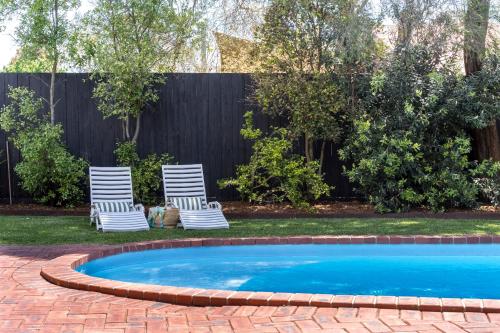 two chairs and a swimming pool in a yard at The Pool House in Rosebud