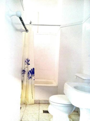 a bathroom with a toilet and a shower curtain with flowers at Hostería Almirante Brown in Mar del Plata