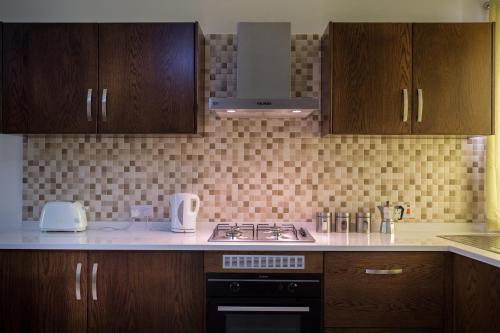 a kitchen with wooden cabinets and a stove top oven at North Side Apartment 1 in Mġarr
