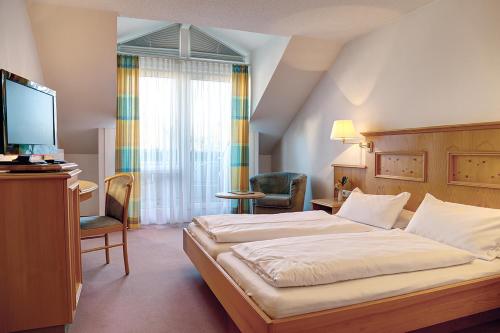 a bedroom with a bed and a desk and a television at Trip Inn Landhotel Krone in Roggenbeuren