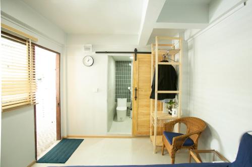 a room with a door and a chair and a toilet at Uncle NID Hostel in Lat Krabang