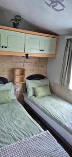 two beds sitting in a room withermottermottermott at Westmorland 32 caravan in Ballantrae