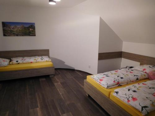 two beds in a room with wooden floors at TaTanKa apartments in Batizovce