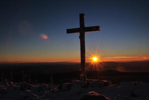 a cross on top of a mountain with the sunset at Zur Alten Dampfsäge - Gasthaus-Pension Weber in Lindberg