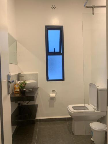 a bathroom with a toilet and a sink and a window at GL Luxe Suites in Tatu City