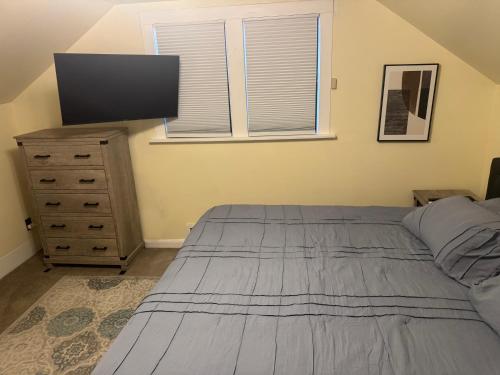 a bedroom with a bed and a dresser with a flat screen tv at Cute as HECK! in Tacoma