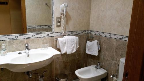 a bathroom with two sinks and a mirror and a toilet at Hotel Reina Isabel in Medina del Campo