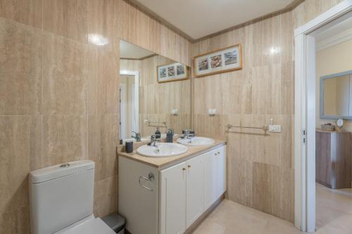 a bathroom with a toilet and a sink and a mirror at Apartamento Duque Beach in Adeje
