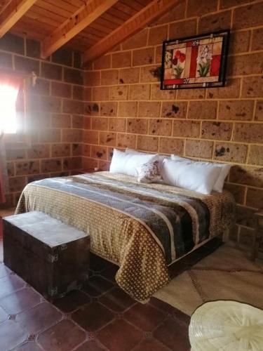 a bed in a room with a brick wall at Villa Rancho el piñón in Ezequiel Montes